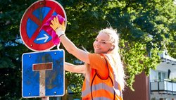 Kollegin in Orange bei der Schilderreinigung