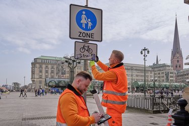 Zwei SRH-Mitarbeiter reinigen ein Schild auf dem Rathausmarkt.