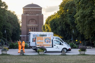 Zwei Reiniger im Stadtpark vor dem Planetarium neben einem Elektroreinigungsfahrzeug 