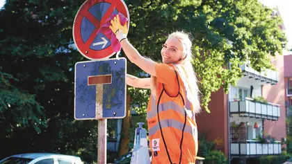 Eine Kollegin bei der Schilderreinigung eines Parkverbotsschilds